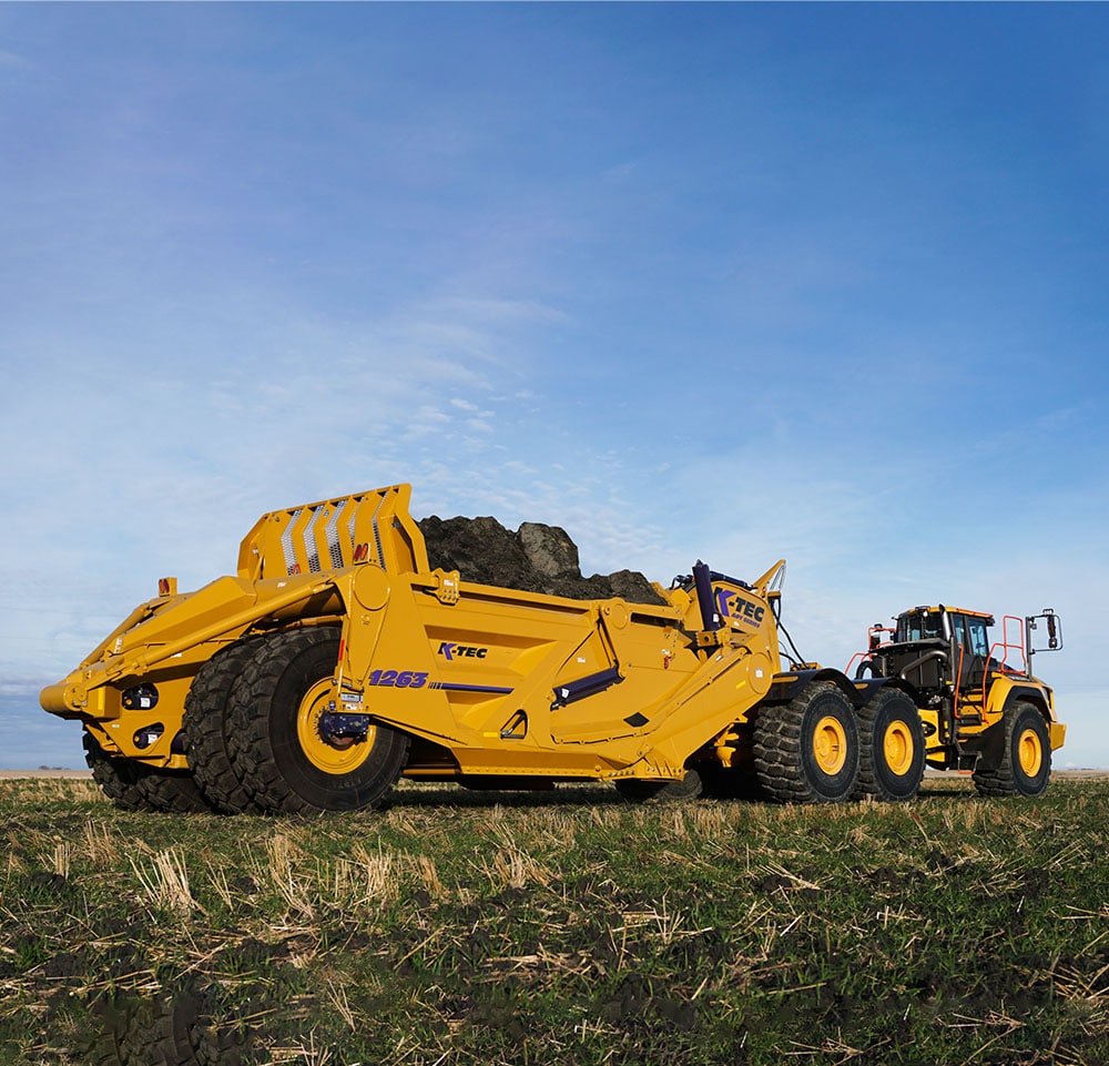 A Versatile 485 tractor pulling a K-Tec 1228 Scraper Pan 