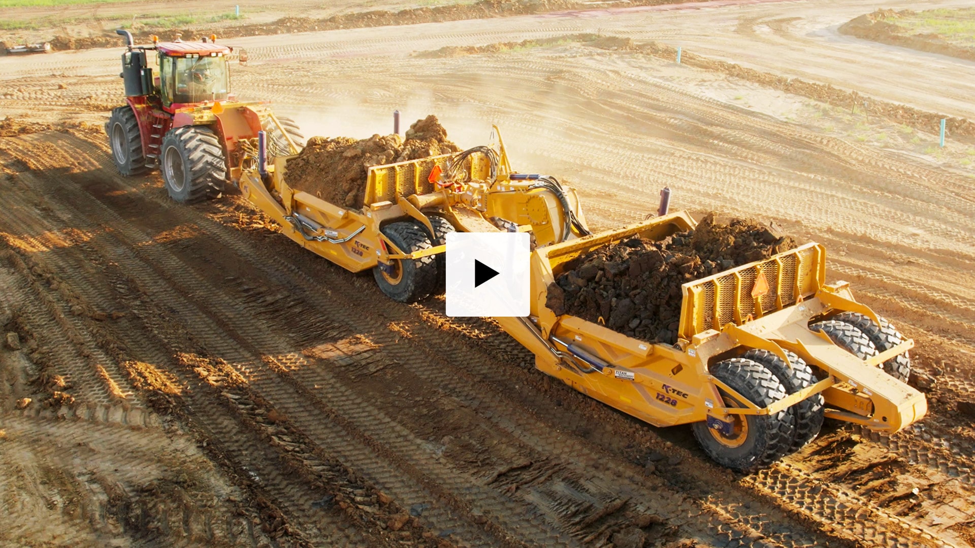 A Versatile 485 tractor pulling a K-Tec 1228 Scraper Pan 